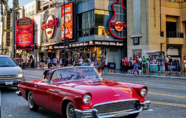 Red Convetible car on a road with the building and crowd at the background
